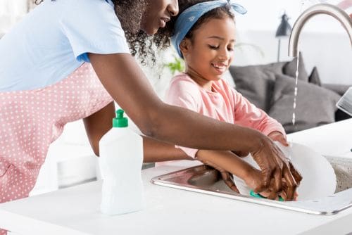Woman and Child washing a plate at a sink Woman and Child washing a plate at a sink