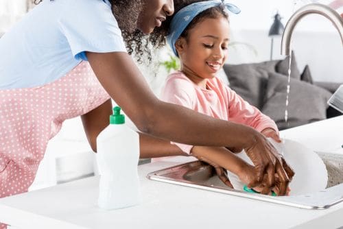 Woman and Child washing a plate at a sink