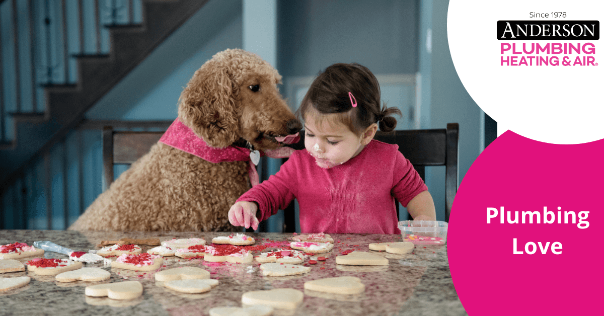 child sitting at a table with a dog making valentine's day cookies
